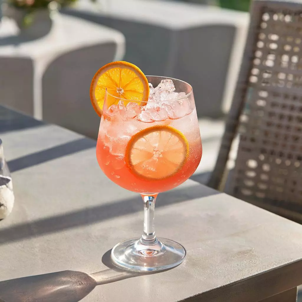 Яркий коктейль Aperol Spritz с апельсиновой долькой и льдом на летней террасе