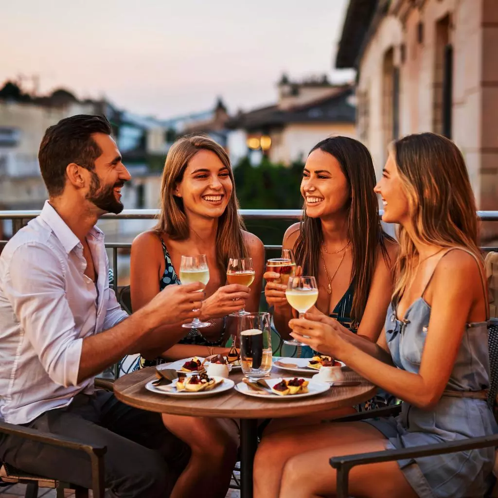 Группа друзей за итальянским Aperitivo на террасе в мягком вечернем свете